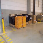 Palettes et colis stockés dans une zone hachurée de sécurité au sol en entrepôt